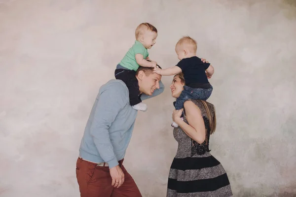 Vater und Mutter spielen mit zwei kleinen Söhnen. Zwei kleine Jungen, Geschwister Zwillinge und Eltern haben Spaß — Stockfoto