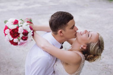 Evlilik çift niteliğine birbirlerine sarılıyor. Beyaz elbiseli güzel model kız. Takım elbiseli adam. Güzellik gelinle damat.