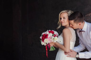 Evlilik çift niteliğine birbirlerine sarılıyor. Beyaz elbiseli güzel model kız. Takım elbiseli adam. Güzellik gelinle damat.