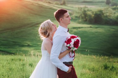 Evlilik çift niteliğine birbirlerine sarılıyor. Beyaz elbiseli güzel model kız. Takım elbiseli adam. Güzellik gelinle damat.