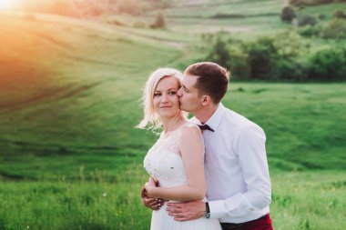 Evlilik çift niteliğine birbirlerine sarılıyor. Beyaz elbiseli güzel model kız. Takım elbiseli adam. Güzellik gelinle damat.