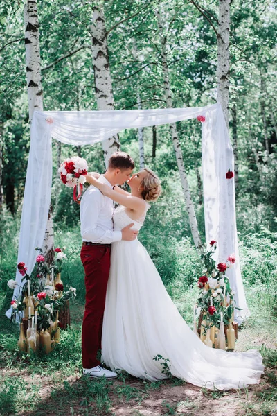 Giovane bella coppia, sposa e sposo nella foresta. Sullo sfondo della decorazione di nozze . — Foto Stock