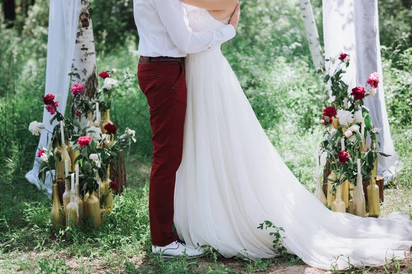 Mladý nádherný pár, nevěsta a ženich v lese. Na pozadí svatební výzdoba. — Stock fotografie