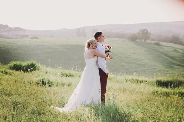 Casal encantador, noiva e noivo posando no campo durante o pôr do sol, estilo de vida — Fotografia de Stock