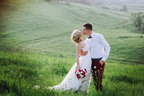 Casal encantador, noiva e noivo posando no campo durante o pôr do sol, estilo de vida — Fotografia de Stock