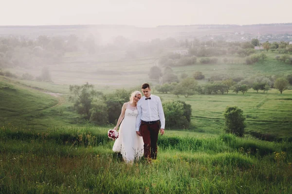 Casal encantador, noiva e noivo posando no campo durante o pôr do sol, estilo de vida — Fotografia de Stock