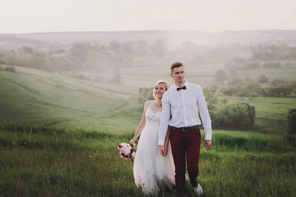 Casal encantador, noiva e noivo posando no campo durante o pôr do sol, estilo de vida — Fotografia de Stock