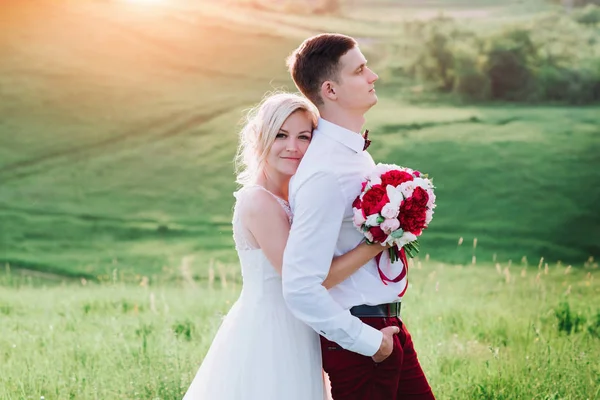 Ζευγάρι γάμο στη φύση το αγκάλιασμα μεταξύ τους. Το όμορφο μοντέλο κορίτσι σε λευκό φόρεμα. Ο άνθρωπος στο κοστούμι. Ομορφιά νύφης με το γαμπρό. — Φωτογραφία Αρχείου