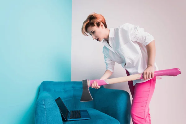 Angry furious businesswoman girl with an ax smashes a laptop, screaming. Negative human emotions, facial expressions, feelings, aggression, anger management issues concept