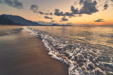 Güneşin doğuşunda kumlu kıyı şeridi ve deniz manzarası 