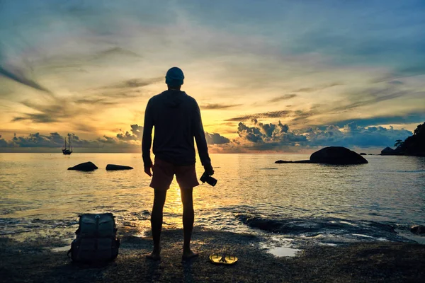 silhouette of male photographer at shore on colorful sunset background