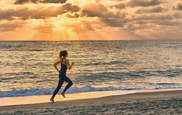 落日背景下在海滩上奔跑的年轻女子 — 图库照片