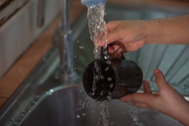 Siyah seramik kahve fincanı lavaboda yıkama el yakın çekim.