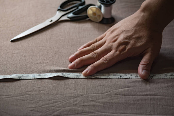 Закрыть руку портного, пытаясь сделать узор на ткани
.