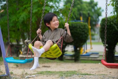 Mutlu Asyalı çocuk giyim Japon bez salıncak parkta oynamaya yakın çekim.