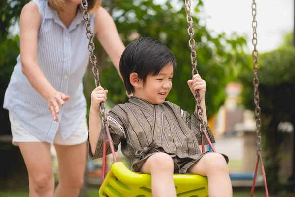 Salıncak park annesi ile oynarken mutlu Asya çocuğun yakın çekim.