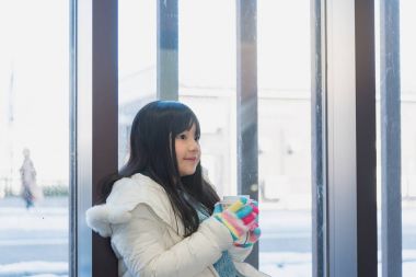 Güzel Asyalı kız sit ve kış tatil kahve fincanı elinde tutan Japonya hokkaido sezon.