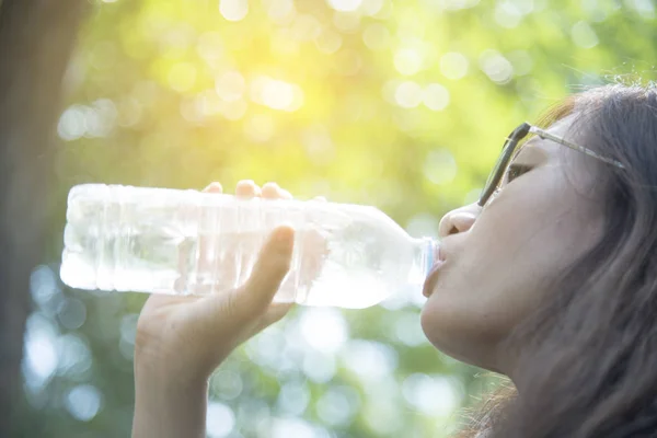 beautiful girl drinks water from a bottle on the nature