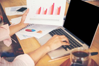 Genç çalışan kadın laptop ve okuma yıllık rapor belge iş kullanarak en iyi görünümü. Masasında çalışan iş kadın.