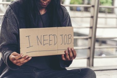 Evsiz, yoksul, dilenci, para isteyen, çaresiz, kirli bir şehirde karton kutunun üstünde 