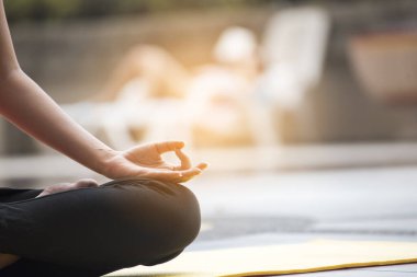 Genç bir kadın yüzme havuzunun yanında yoga yapıyor. Sağlık hizmetleri kavramı.