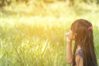 Cute girl play blowing bubble on playground with hard sun light. Little Kids enjoy and fun on play yard.