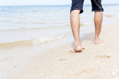 Genç yakışıklı adam plajda rahatlıyor ve yürüyor. Seyahat kavramı