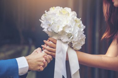 Benimle evlenir misin? Evet, biliyorum. Nişan aşığı romantik bir törenle beyaz düğün buketi veriyor. Sürpriz evlilik teklifinden sonra çift romantizmi. Sevgililer Günü aşk kavramı.