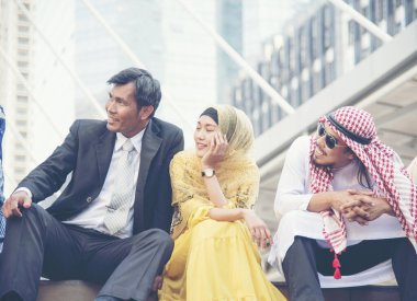 Çok ırklı bir grup modern şehir üzerinde çalıştıktan sonra arka planda oturup rahatlıyor. İş dünyasındaki bir grup insan çeşitliliği.