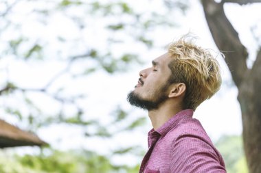 Yakışıklı adam, derin nefes al. Parkta gözlerini dinlendir. Derin bir nefes al ve mutluluğu hisset. Dinlenmiş ve mutlu.