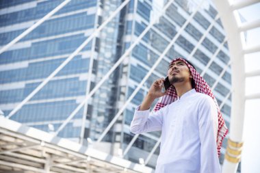 Akıllı tablet kullanan yakışıklı, modern Arap adam. Arap adam şehirde yürürken akıllı telefon kullanıyormuş. İş başarısı kavramları.