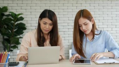 Mutlu girişimci Asyalı iş kadınları akıllı telefon pazarlığını yeni bir iş kurmak için kullanıyorlar. İki ortak akıllı telefonlardan iyi haberler alıyor. İş birliği yapan Asyalı kadın birlikte çalışıyor.