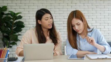Mutlu girişimci Asyalı iş kadınları akıllı telefon pazarlığını yeni bir iş kurmak için kullanıyorlar. İki ortak akıllı telefonlardan iyi haberler alıyor. İş birliği yapan Asyalı kadın birlikte çalışıyor.