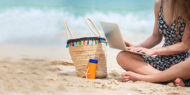 Yaz zamanı kumsalda bronz tenli kadın tatili. Neşeli kadın sahilde oturmuş denize bakarken yazlık elbiseler ve hasır şapkalar giyiyor. Yazın tropik ada sahilinde açık hava çekimlerinde dinlenme zamanı..