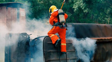 İtfaiyeci yangın hortumuyla, kimyasal köpüklü sprey motorla savaşıyor. İtfaiyeciler korunmak için kasketli, vücut korumalı üniformalı üniforma giyer. Yangın söndürücüde kurtarma eğitimi.