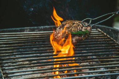 Izgara ızgara et, ateş alevi, bbq yemek pişirme, kömürden yanıyor. Biftek ızgarası, ateş ve dışarıda sigara içmek. Parti için açık havada biftek ızgara. Batı yemekleri konsepti