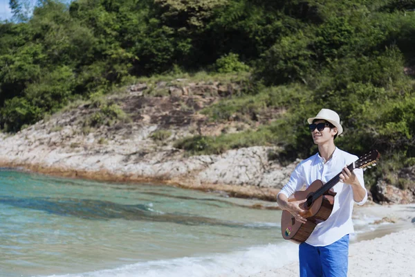 Young man travel outdoor on tropical beach with blue sky and white cloud using DSLR professional camera take a photo on vacation time with love nature. Outdoor travel lifestyle concept.