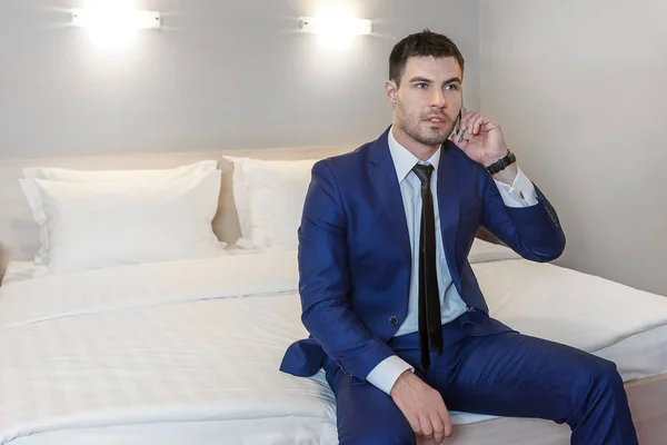 Young businessman working in his hotel room and talks to a client on the phone
