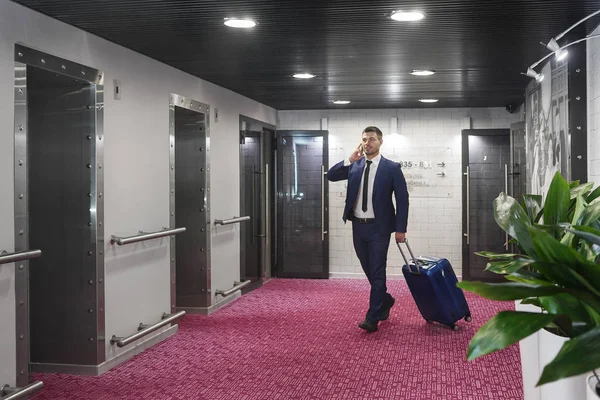 Young businessman with luggage in hotel lobby