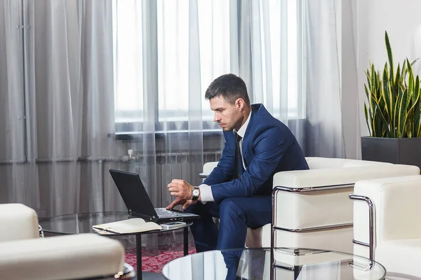 Young businessman working at laptop in lobby