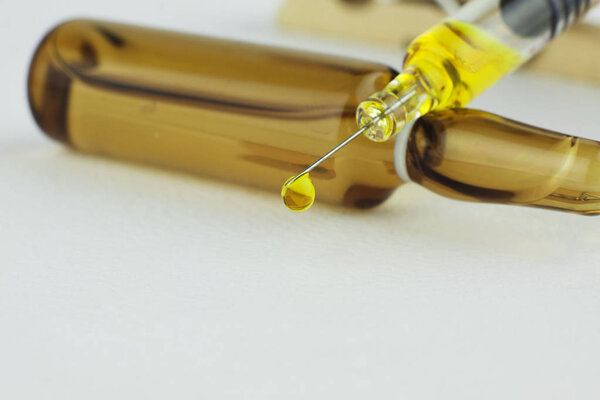 Yellow drop falling from the top of the syringe