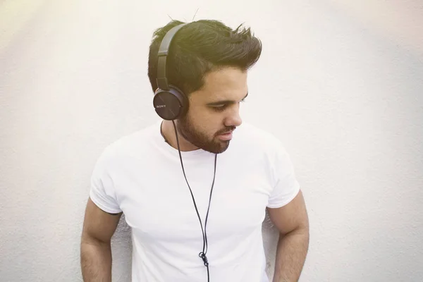 Joven guapo escuchando la música en los auriculares . — Foto de Stock