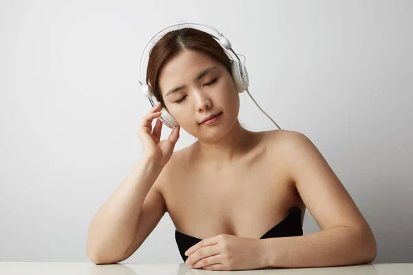 Słuchanie muzyki przez słuchawki na białym tle miłej kobiety. Portret z bliska. — Zdjęcie stockowe