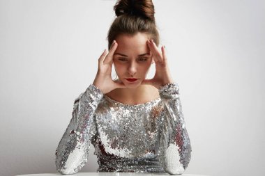 Beyaz duvara gece elbisesi giyen neşeli genç kadın.