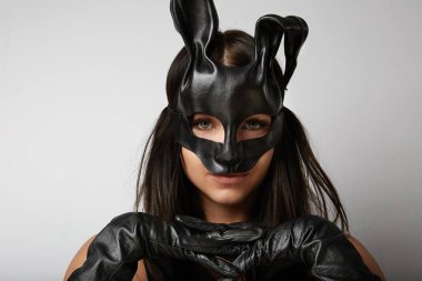 Siyah maske Paskalya bunny ayakta beyaz bir arka plan ve görünüyor çok sensually giymiş seksi kadın.