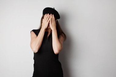 Kadın elleriyle yüzünü gizleme. Beyaz bir arka plan üzerinde.