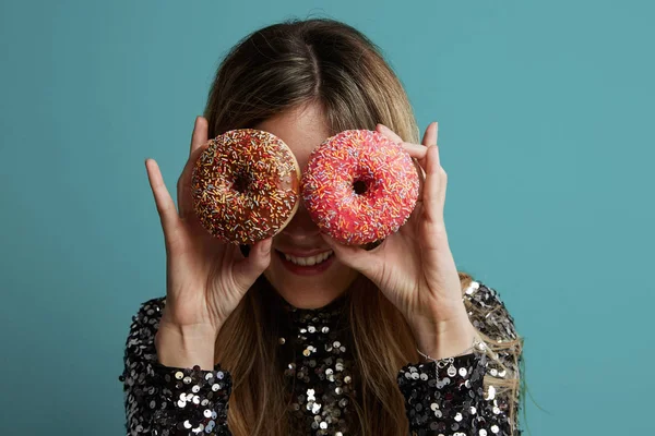 Beautiful girl is looking at unhealthy donut with appetite. Isolated on a colorful background. — Stock Photo, Image