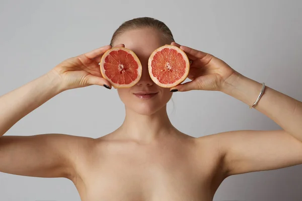 Close-up van portret de blonde vrouw houden de helft een oranje geïsoleerd op de witte achtergrond — Stockfoto