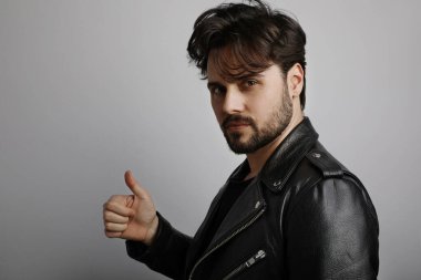 Stüdyo, genç sakallı hipster 'ın yakın plan portresi kameraya bakıyor ve OK' u eliyle gösteriyor..
