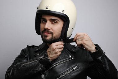 Kameraya bakıp kaskını takan genç ve yakışıklı motorcunun portresini yakından çek..
